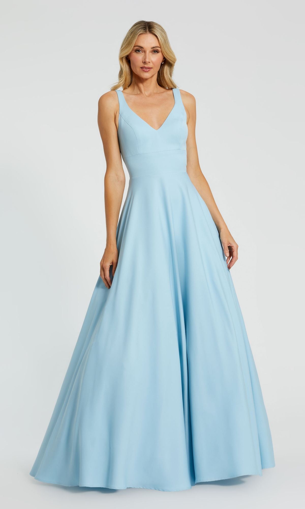 A woman stands against a plain white background wearing the Mac Duggal 48924 Classic Long Prom Ball Gown, featuring a fitted bodice and flared, floor-length skirt in light blue.